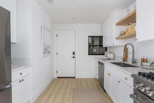 kitchen featuring light wood-type flooring, white cabinets, stainless steel appliances, and sink