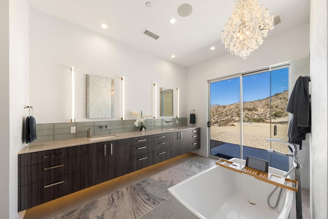 bathroom featuring an inviting chandelier, vanity, a mountain view, and a tub