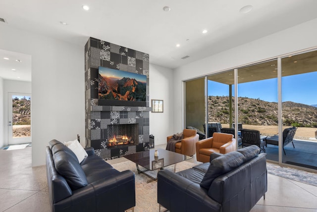 living room featuring a tiled fireplace and a wealth of natural light