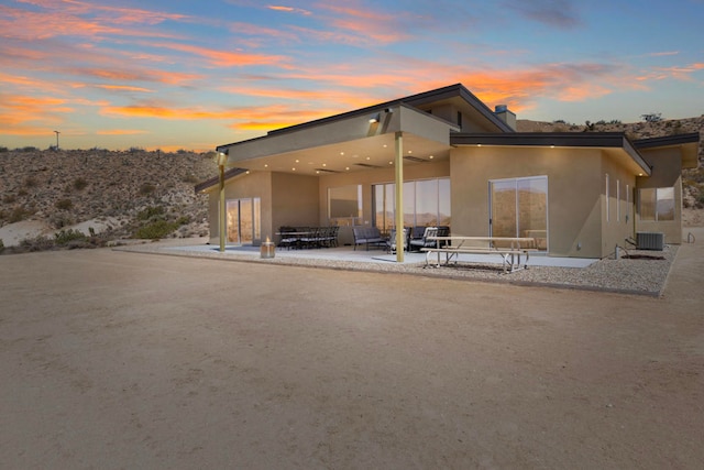 back house at dusk with a patio and central AC