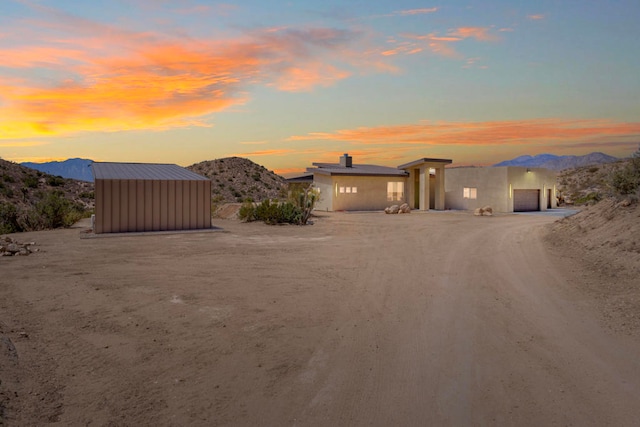 view of front facade featuring a mountain view, a storage unit, and a garage