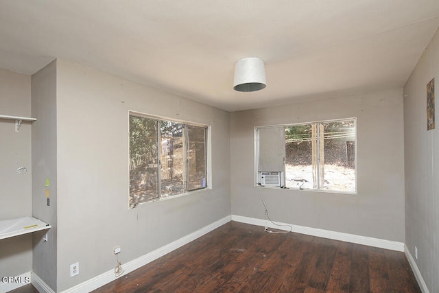 unfurnished room with cooling unit, dark hardwood / wood-style floors, and a wealth of natural light