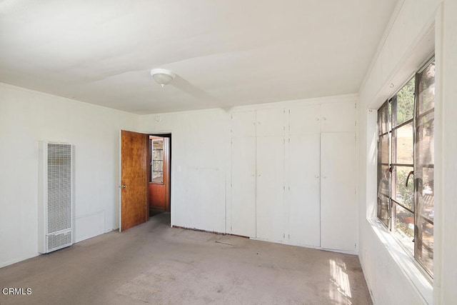 unfurnished bedroom with ornamental molding, a closet, and light carpet