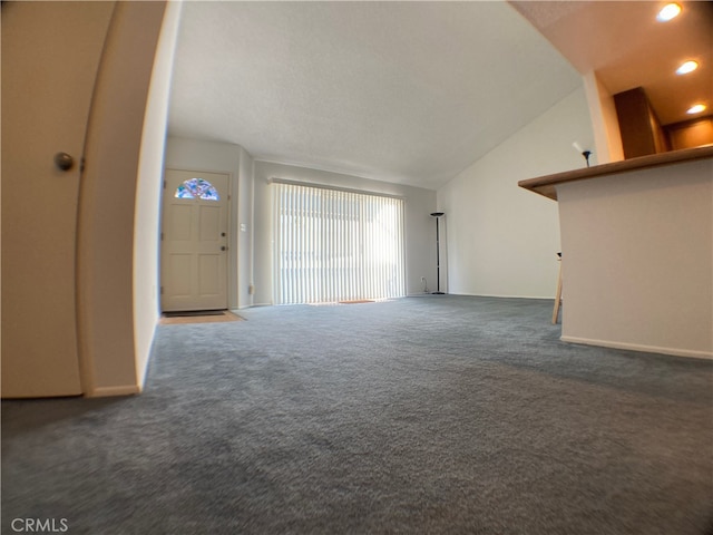 unfurnished living room featuring dark carpet and vaulted ceiling