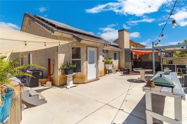 back of house with solar panels, a patio area, and central air condition unit