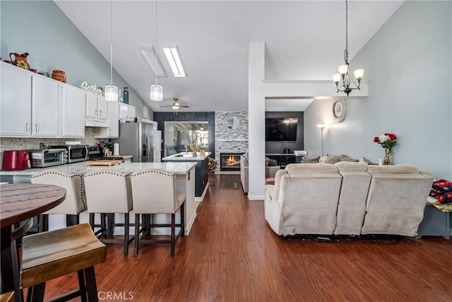 kitchen featuring ceiling fan with notable chandelier, white cabinetry, dark hardwood / wood-style flooring, stainless steel fridge with ice dispenser, and a breakfast bar area