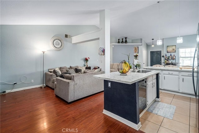 kitchen featuring white cabinetry, sink, hardwood / wood-style floors, lofted ceiling, and a center island with sink