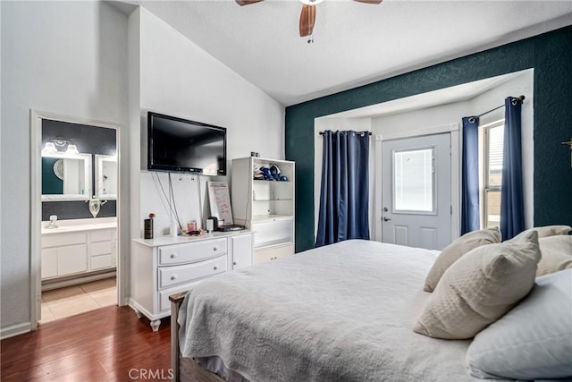 bedroom featuring ceiling fan, ensuite bathroom, dark wood-type flooring, and lofted ceiling