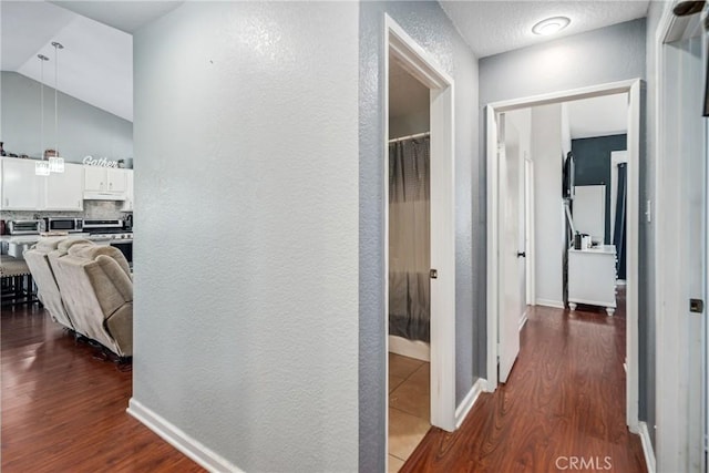 corridor with hardwood / wood-style floors and lofted ceiling