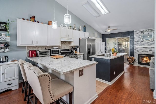 kitchen featuring hanging light fixtures, ceiling fan, appliances with stainless steel finishes, a kitchen island, and white cabinetry