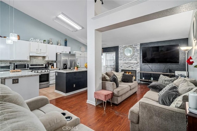 living room with a fireplace, high vaulted ceiling, and dark wood-type flooring