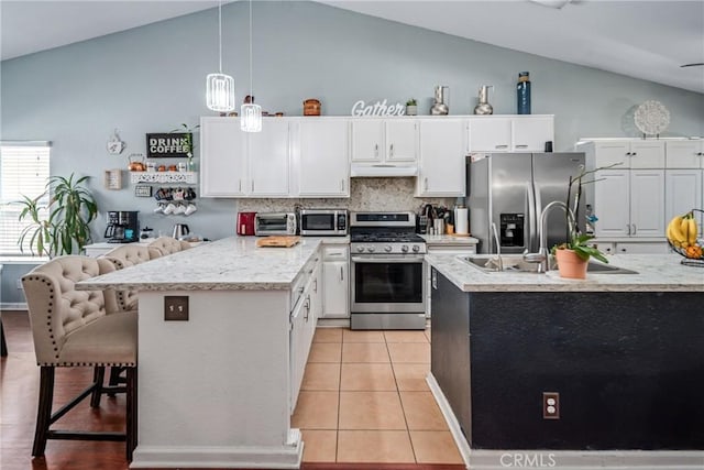 kitchen with appliances with stainless steel finishes, a breakfast bar, sink, pendant lighting, and white cabinetry