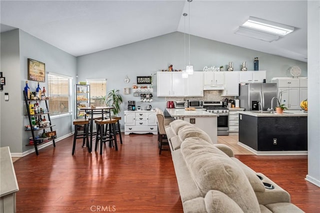 kitchen featuring a center island with sink, hanging light fixtures, dark hardwood / wood-style floors, and appliances with stainless steel finishes