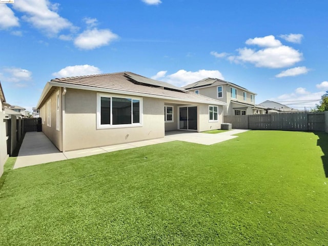 rear view of house with a yard, a patio, and solar panels