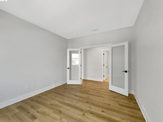 spare room featuring light wood-type flooring and french doors