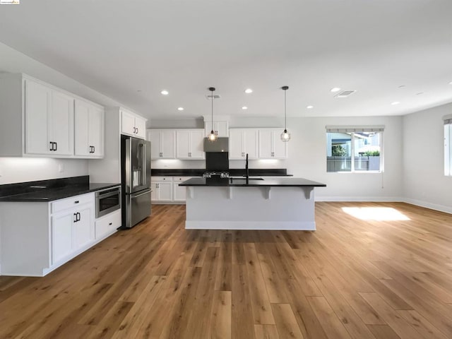 kitchen with hardwood / wood-style flooring, pendant lighting, white cabinetry, and appliances with stainless steel finishes