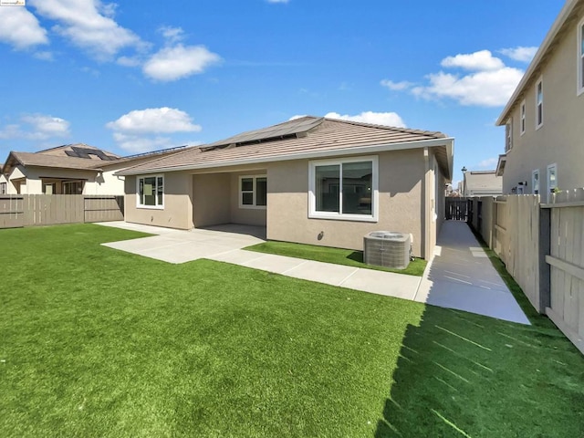 back of property featuring solar panels, a patio, cooling unit, and a yard