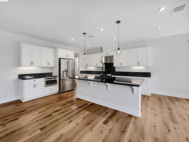 kitchen featuring appliances with stainless steel finishes, light hardwood / wood-style flooring, and white cabinetry