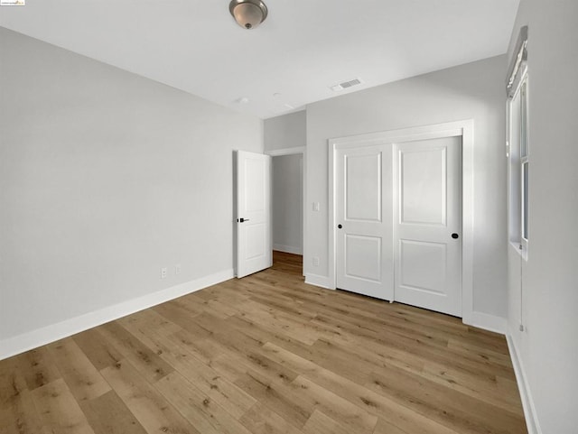 unfurnished bedroom with light hardwood / wood-style flooring and a closet