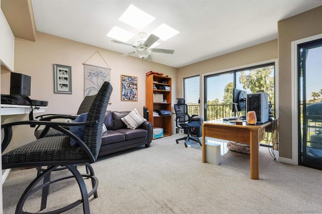 home office featuring light carpet, ceiling fan, and a skylight