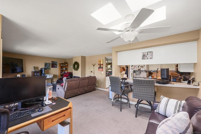 living room with a skylight, light colored carpet, and ceiling fan