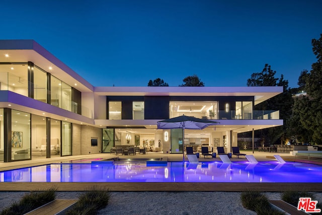 back house at twilight featuring a patio