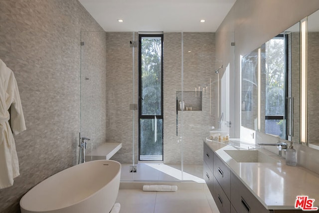 bathroom featuring tile walls, vanity, expansive windows, tile patterned floors, and independent shower and bath