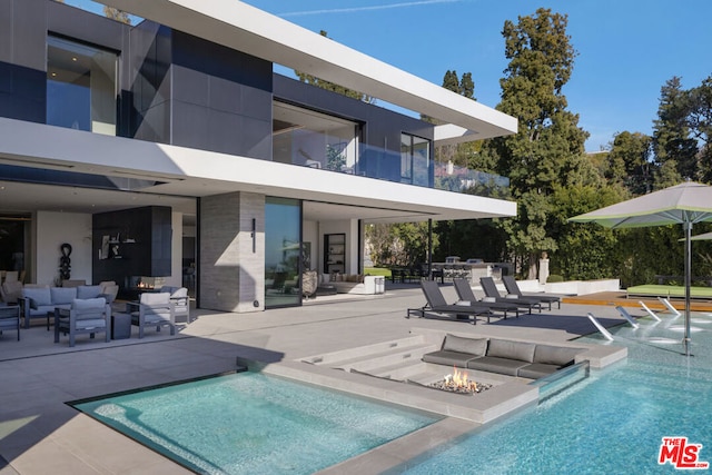 view of pool with an outdoor living space with a fire pit, a patio area, and a jacuzzi