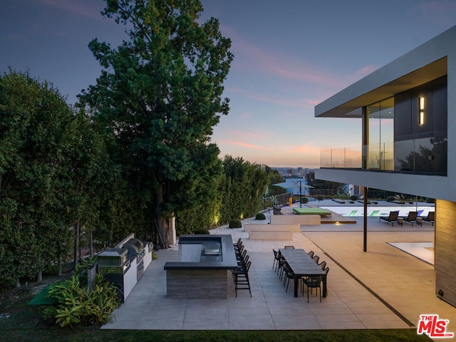 patio terrace at dusk with an outdoor bar and an outdoor kitchen