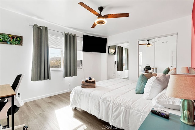 bedroom featuring hardwood / wood-style flooring, two closets, and ceiling fan