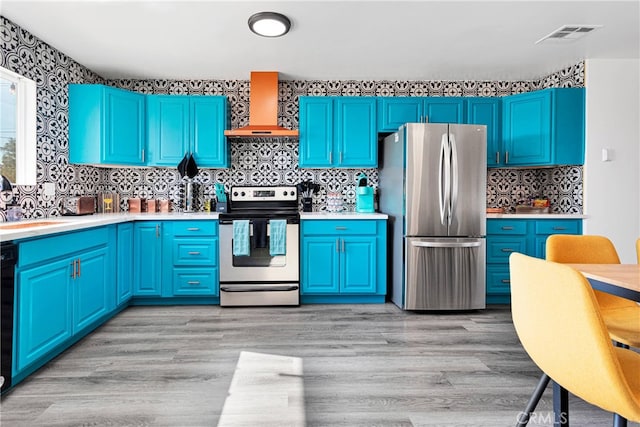 kitchen with decorative backsplash, wall chimney range hood, light hardwood / wood-style flooring, stainless steel appliances, and blue cabinetry