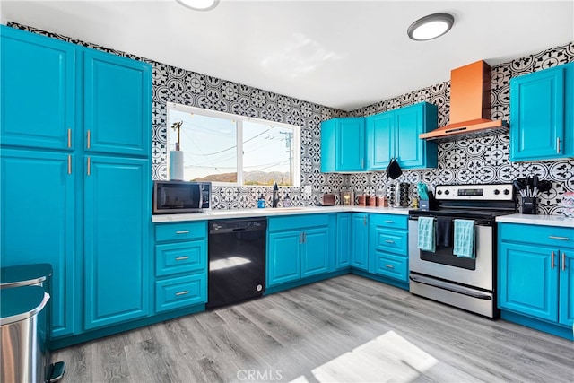 kitchen featuring tasteful backsplash, blue cabinetry, light hardwood / wood-style flooring, wall chimney exhaust hood, and stainless steel appliances