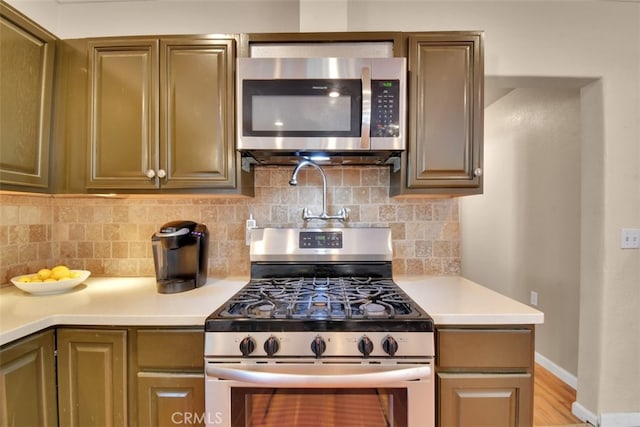 kitchen featuring tasteful backsplash, stainless steel appliances, and light wood-type flooring