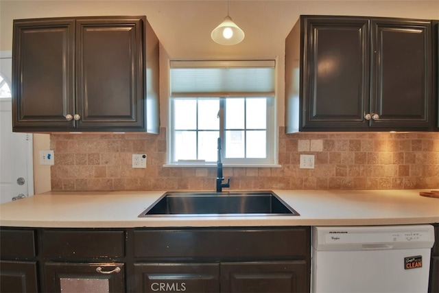 kitchen with sink, white dishwasher, pendant lighting, and backsplash