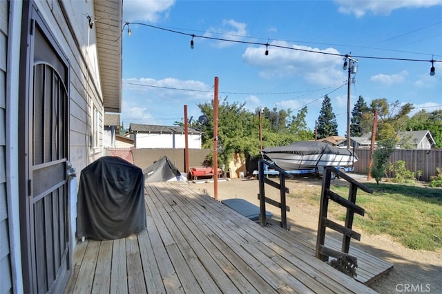 wooden terrace with a lawn and a grill