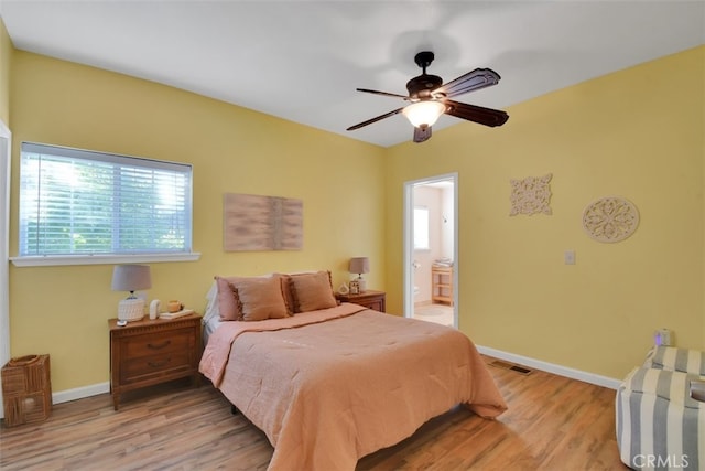 bedroom with light hardwood / wood-style floors, ensuite bathroom, and ceiling fan