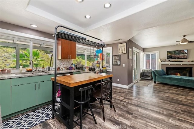 kitchen with dark wood-type flooring, a wealth of natural light, a sink, and a lit fireplace