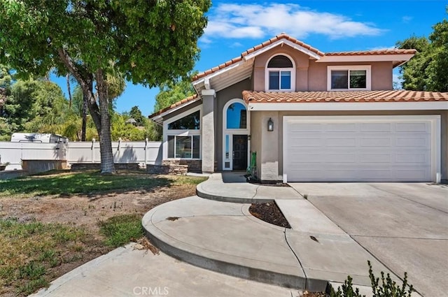 mediterranean / spanish-style house featuring a garage, a tile roof, fence, and stucco siding