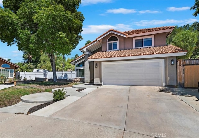 view of front facade featuring a tile roof, fence, concrete driveway, and stucco siding