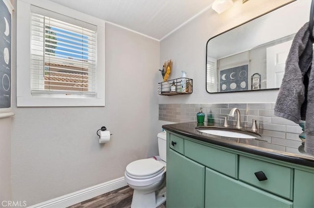 half bath with baseboards, decorative backsplash, toilet, wood finished floors, and vanity