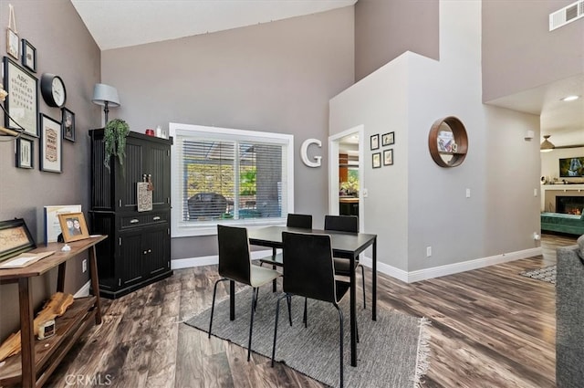 dining area featuring dark hardwood / wood-style floors and high vaulted ceiling