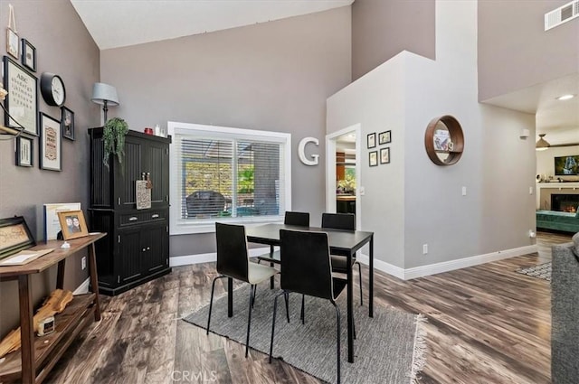 dining area featuring a high ceiling, visible vents, dark wood finished floors, and baseboards