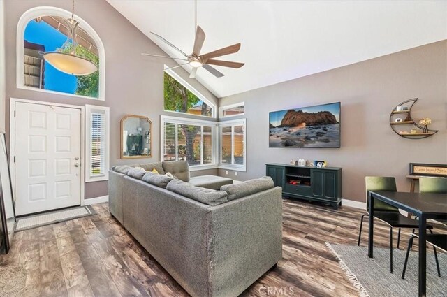 living area featuring high vaulted ceiling, ceiling fan, baseboards, and wood finished floors