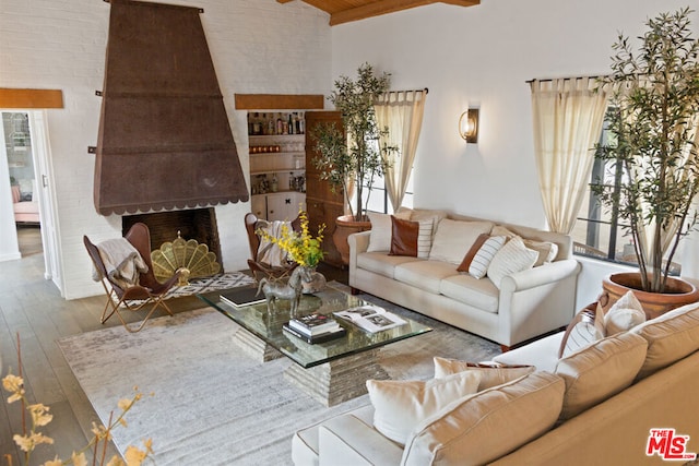 living room featuring a brick fireplace, vaulted ceiling, brick wall, and hardwood / wood-style floors