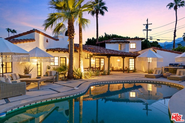 pool at dusk featuring a patio area