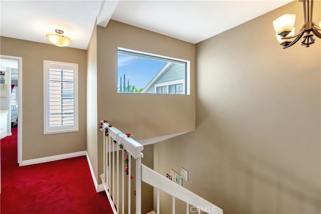 hall with carpet floors and an inviting chandelier