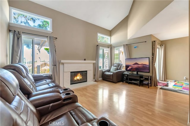 living room with wood-type flooring, a fireplace, and high vaulted ceiling