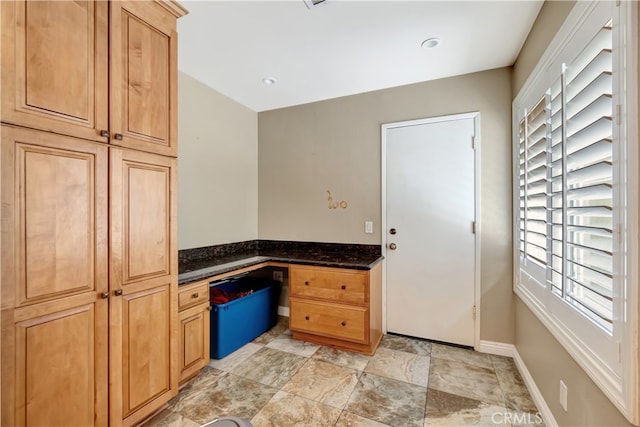 kitchen with dark stone counters and built in desk