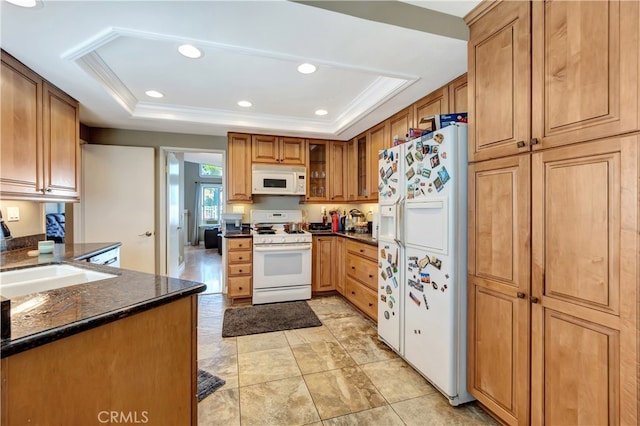 kitchen with ornamental molding, sink, white appliances, a tray ceiling, and dark stone countertops