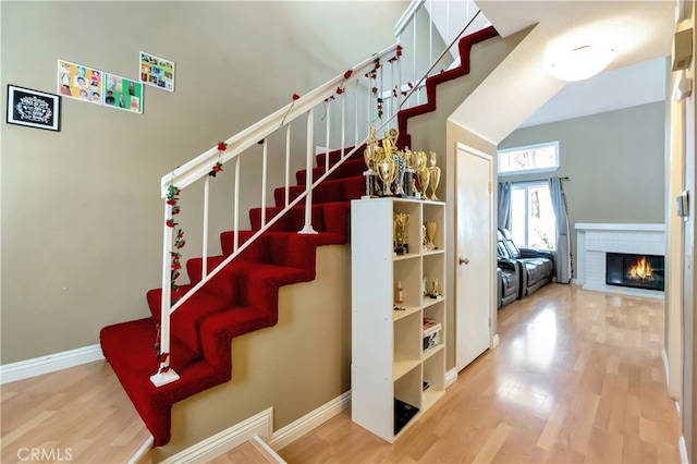 stairs featuring a brick fireplace and hardwood / wood-style flooring